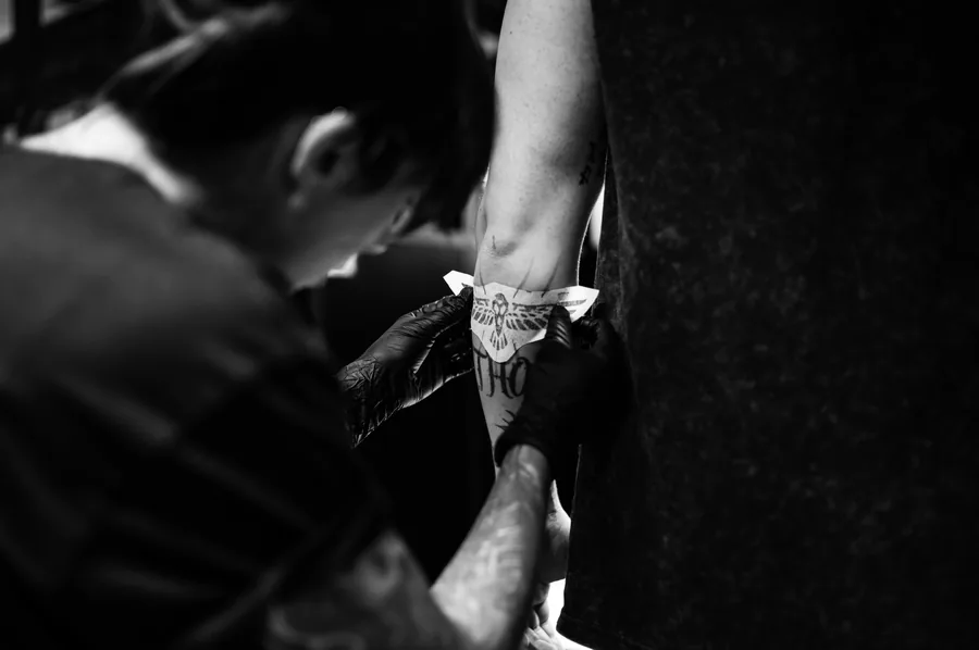 Detalle de María tatuando un brazo apoyado en la camilla.