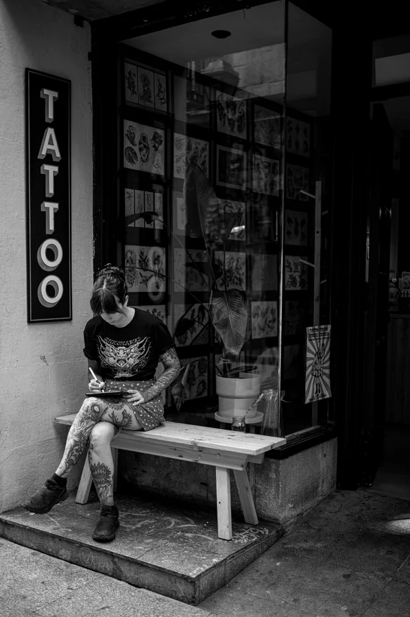 Entrada del estudio con el rótulo TATTOO y la pared de láminas.