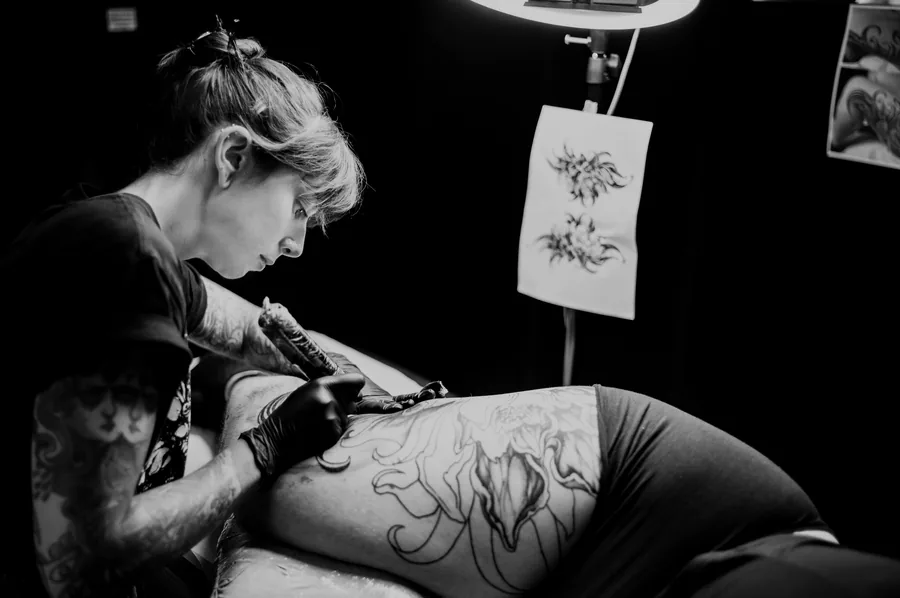 María tatuando una espalda con el calco colgado a un lado.