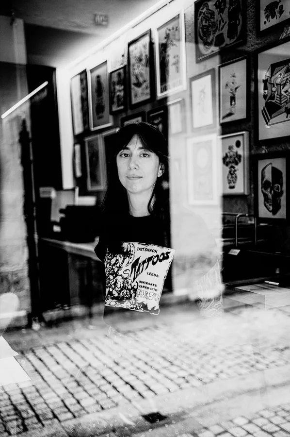 María en la puerta del estudio con la calle empedrada al fondo.