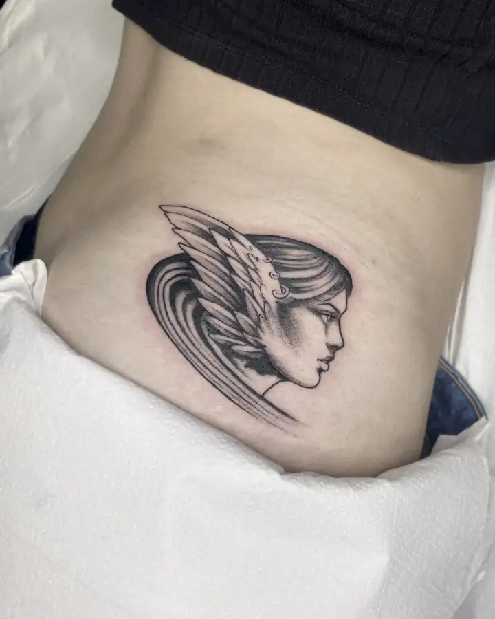 Cadera con el perfil de una mujer tocada con un casco alado, en black & grey de sombreado suave.