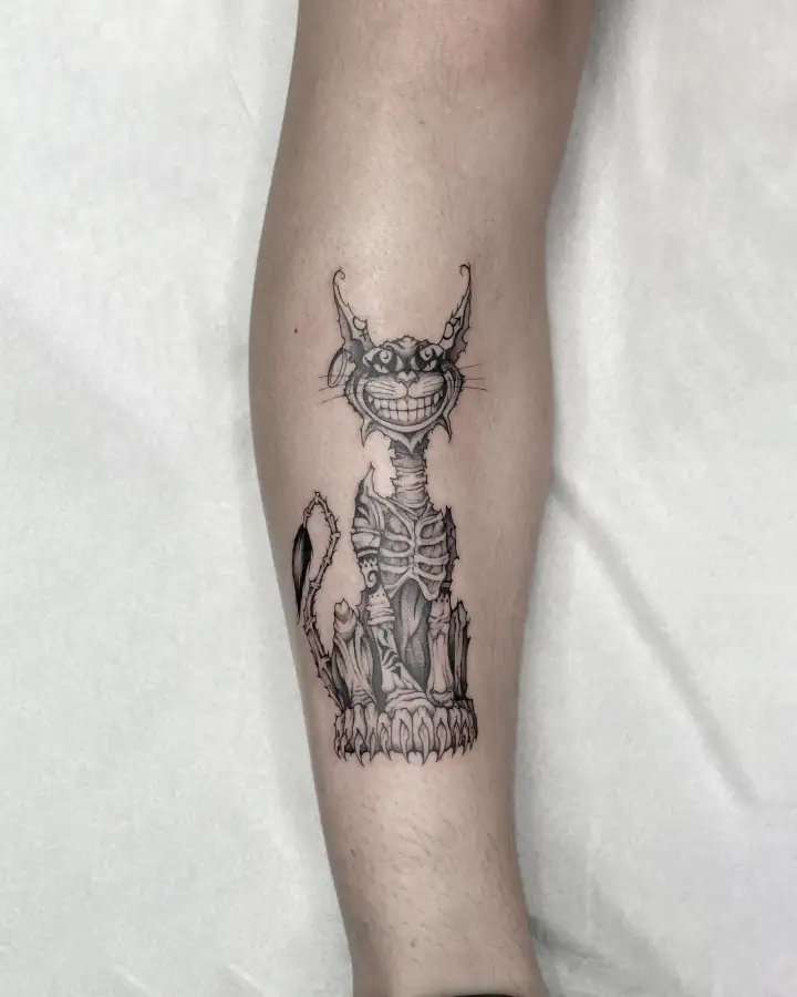 En el antebrazo, un gato sonriente de cuerpo esquelético sobre un pedestal, a línea fina con sombreado suave.