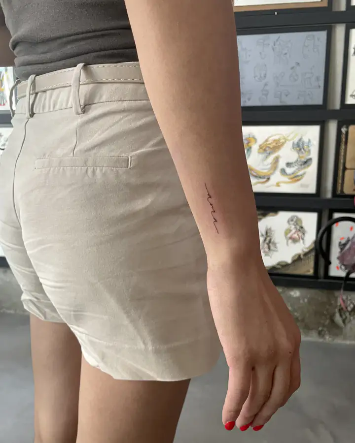 Antebrazo con un pequeño trazo manuscrito, resuelto en una única línea fina continua.