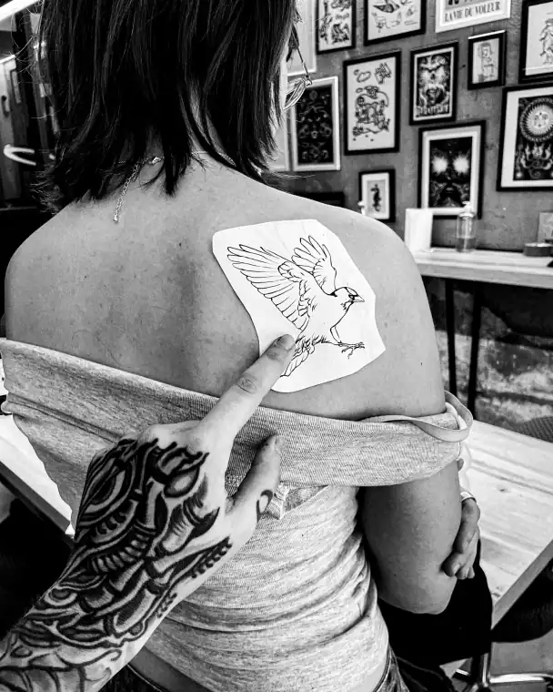 Hombro con el calco de un ave de alas abiertas, dibujado a línea y colocado antes de empezar a tatuar.