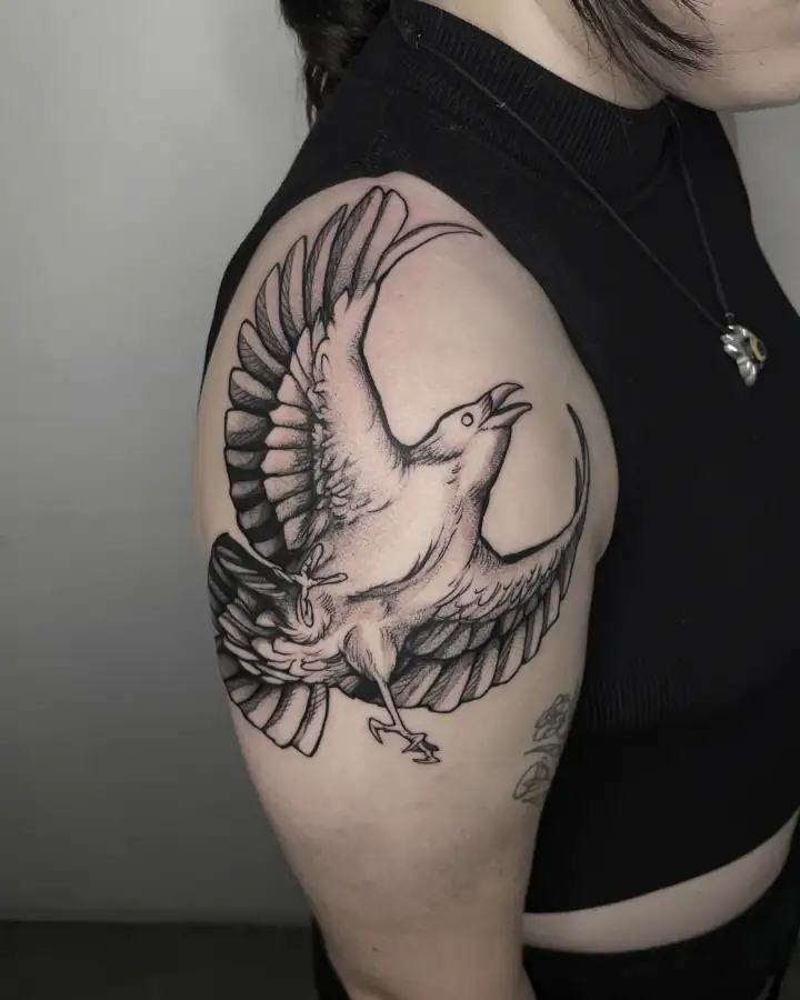 Hombro con un ave de alas abiertas y el pico alzado, en black & grey con sombreado de trazos finos.