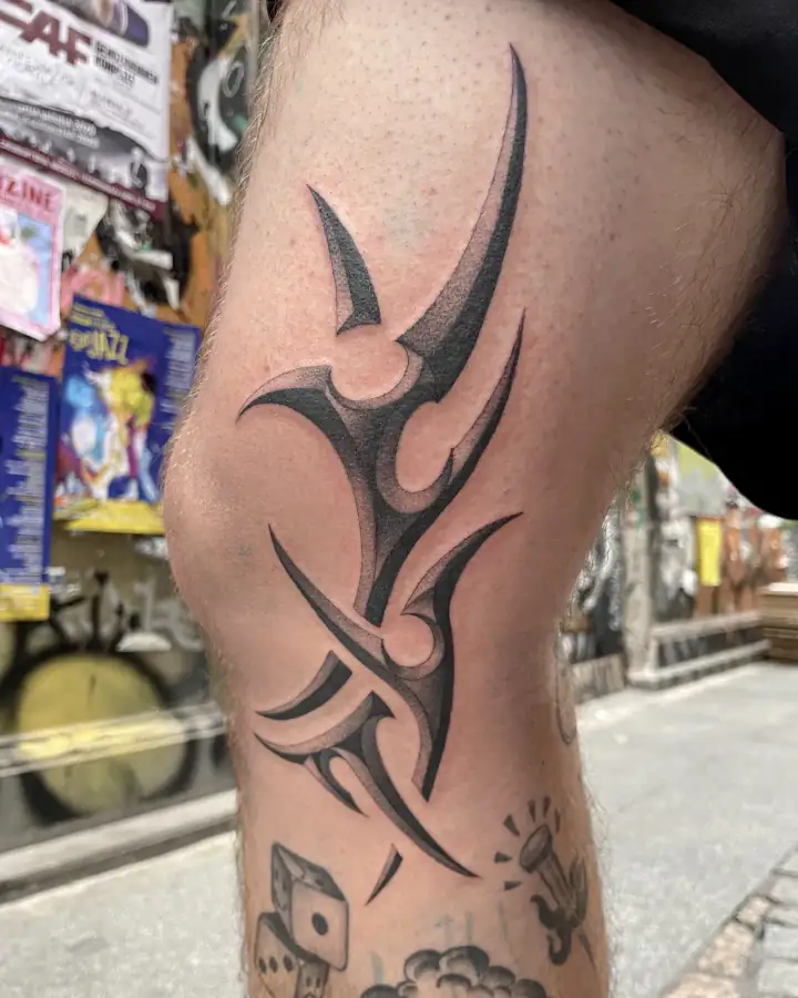 Rodilla con una forma tribal de puntas afiladas, en negro sólido y degradado gris.