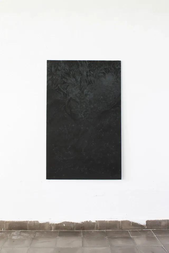 Pintura vertical oscura colgada en una pared blanca sobre un zócalo de baldosas; en su parte superior se distinguen formas vegetales claras.