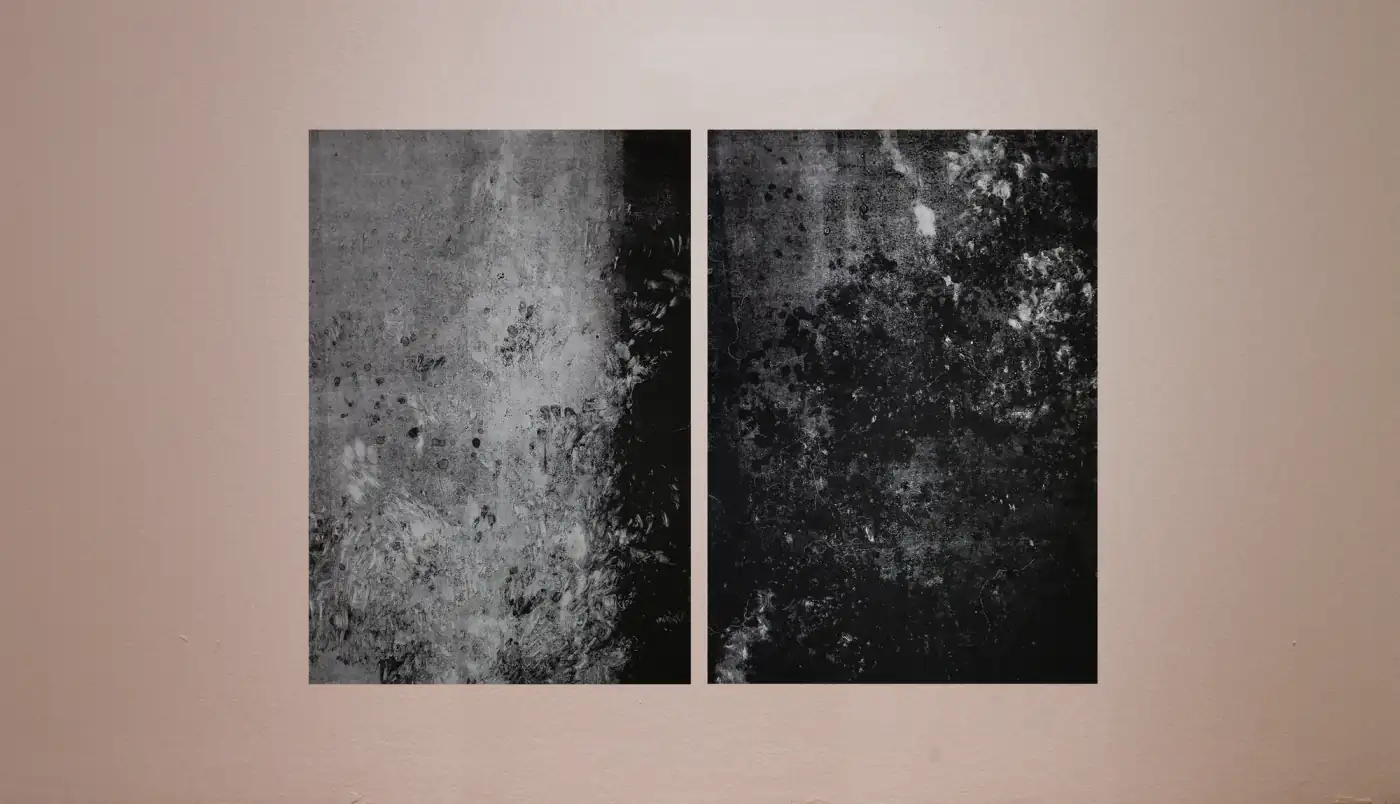 Dos paneles verticales en grises colgados uno junto al otro en la pared de una sala: el izquierdo claro con franja negra a la derecha, el derecho oscuro y moteado.