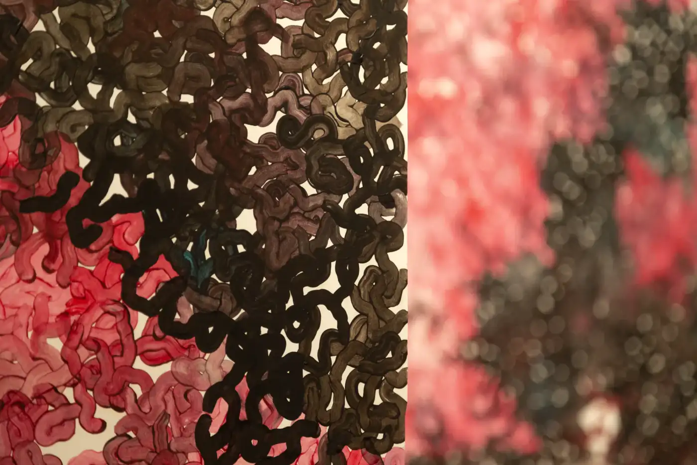 MUR MUR (detalle), pintura sobre papel (2018). Detalle cercano de bucles pintados negros y rosas; al fondo, el mural rosa desenfocado.