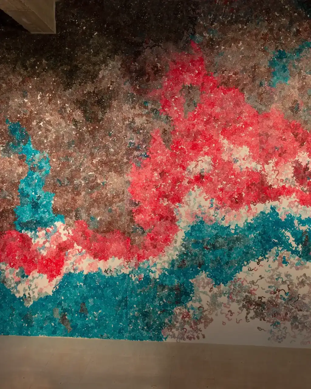 MUR MUR, pintura sobre papel (2018). Fragmento 3 de 6 de la panorámica del mural de pintura sobre papel: formas rojas entrelazadas en el centro, turquesa a la izquierda y en la parte inferior, y zonas pardas y rosadas alrededor.
