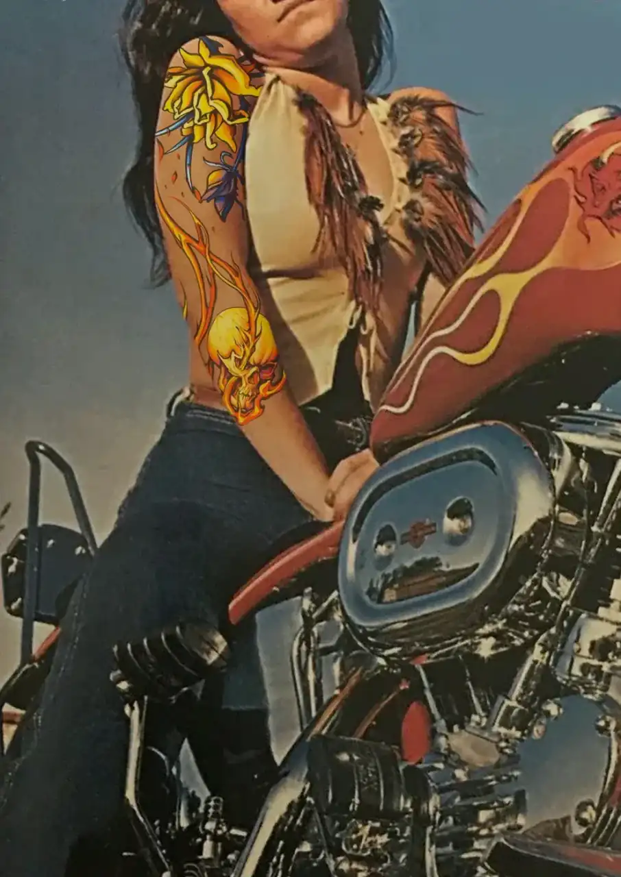 Diseño de María Vera mostrado en mockup sobre una fotografía de archivo: mujer sentada en una Harley con chaleco de flecos, con un dragón amarillo y naranja cubriéndole brazo y costado.
