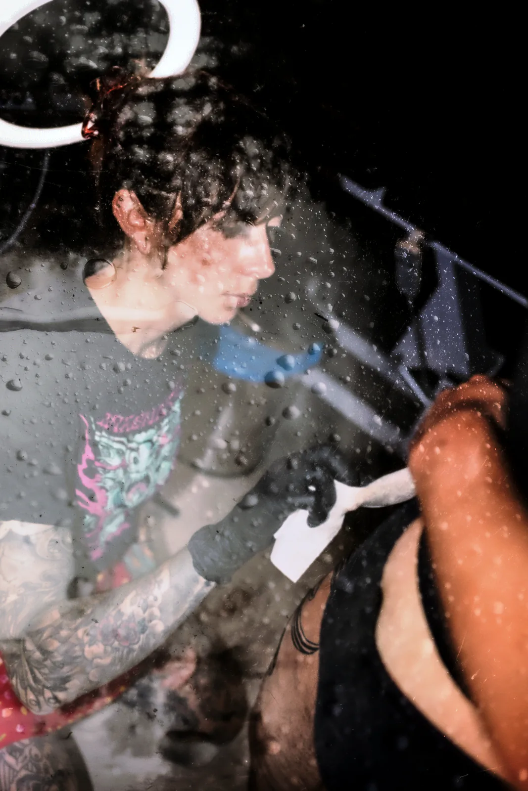 Retrato con reflejo y doble exposición de una persona de pelo rizado tatuando; textura de gotas.