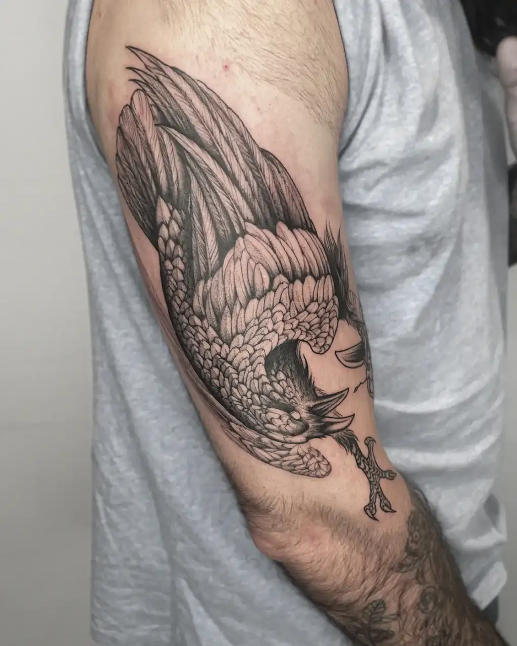 Brazo con un ave en picado y las alas desplegadas, plumaje detallado en línea fina y dotwork.