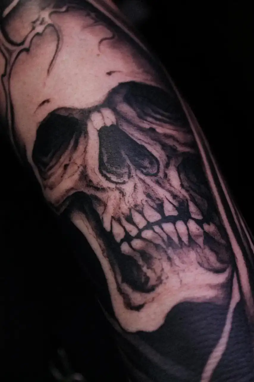 Brazo con una calavera modelada solo a base de sombra, en black & grey de acabado realista.