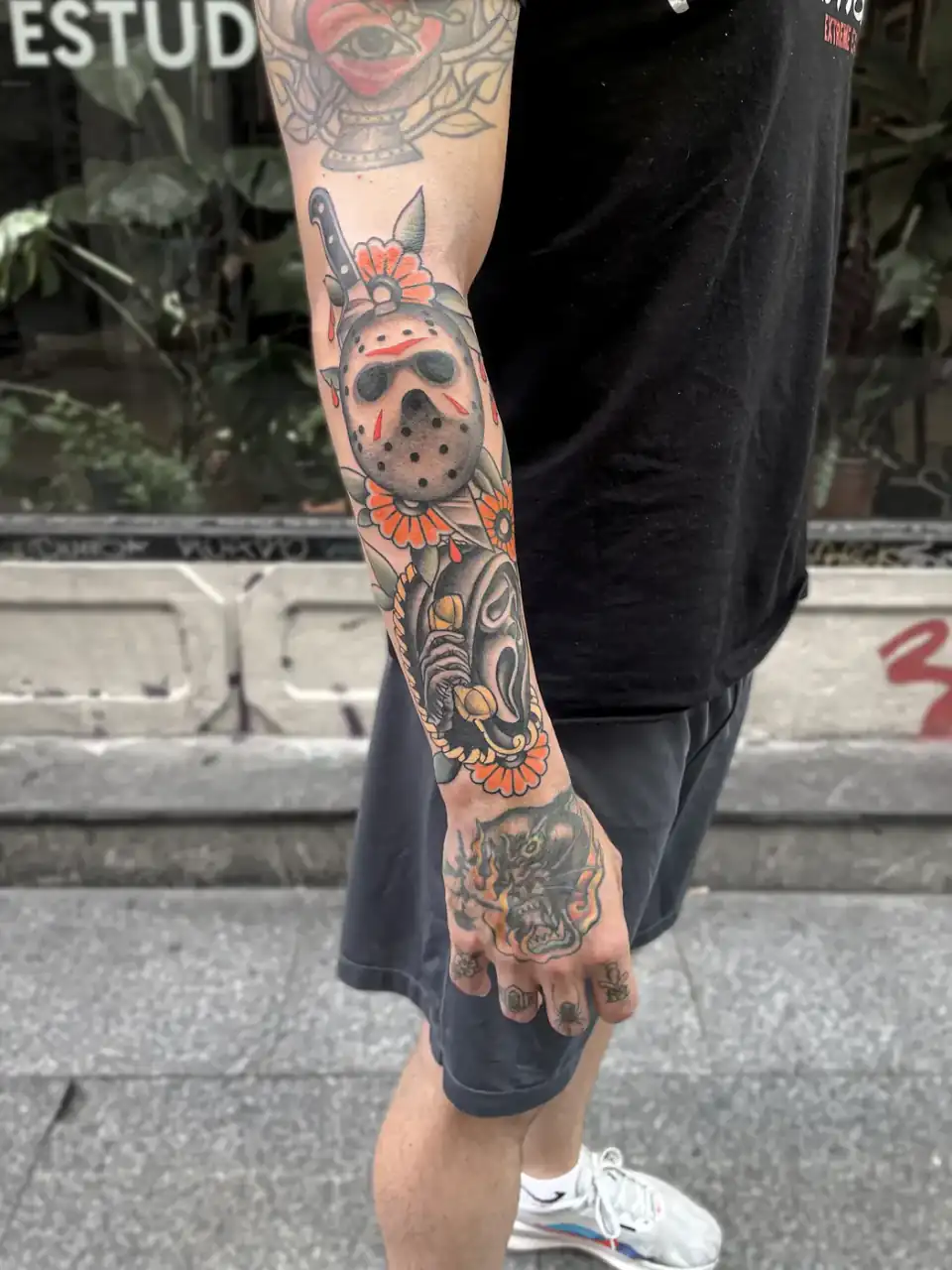 Brazo entero: una manga a color de máscaras de cine de terror y margaritas naranjas, en tradicional old school.