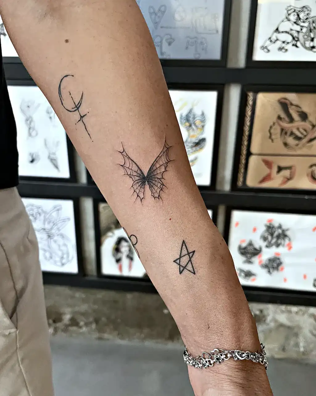 Microtatuajes fineline en el antebrazo delante de una pared de flash.