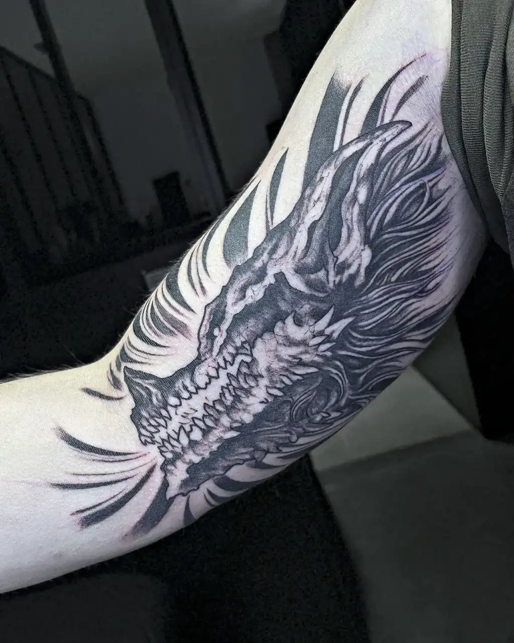 Cráneo de dragón entre humo en blackwork denso, cara interna del brazo.